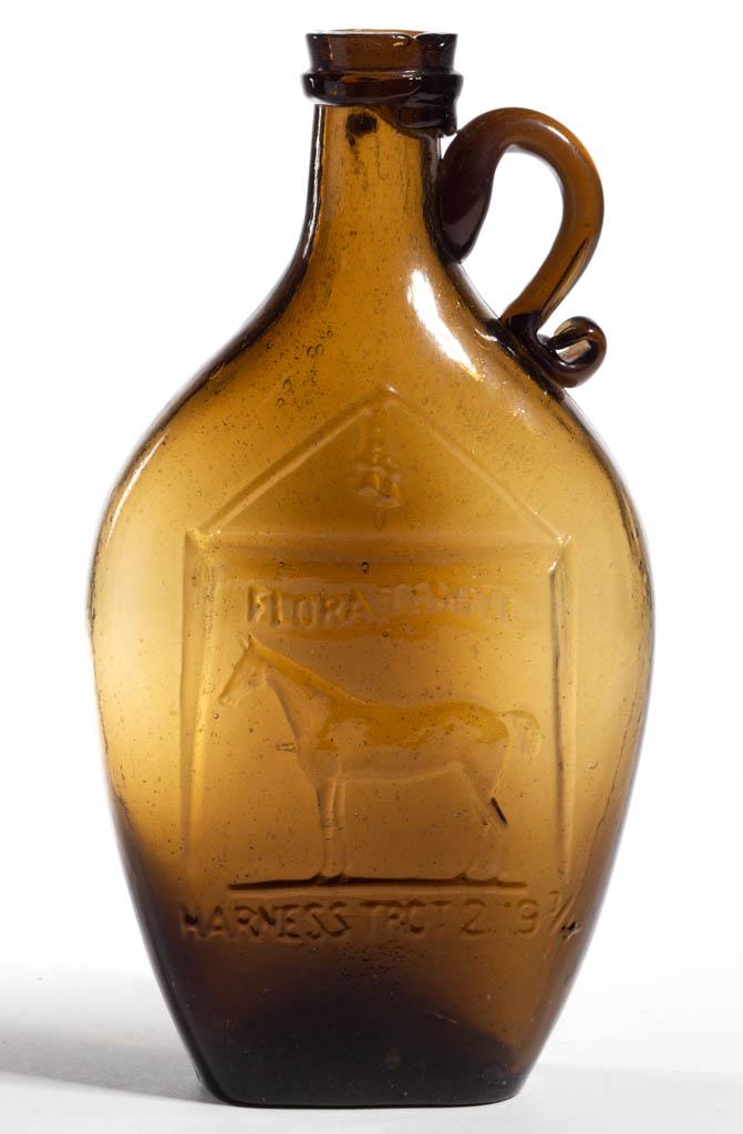 GXIII-24 FLORA TEMPLE PICTORIAL HANDLED FLASK: GXIII-24 FLORA TEMPLE PICTORIAL HANDLED FLASK, medium yellow olive green, pint, embossed on obverse "FLORA TEMPLE" above racehorse with "HARNESS TROT 2.19 3/4" below, applied handle, applied flat coll
