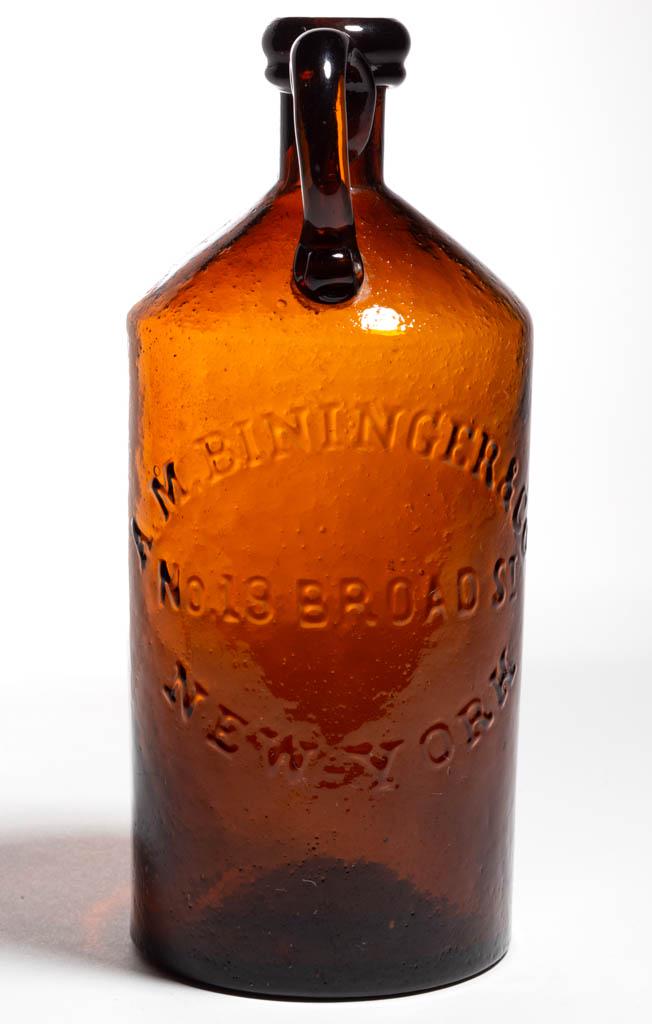 BININGER'S HANDLED WHISKEY BOTTLE: BININGER'S HANDLED WHISKEY BOTTLE, medium brown amber, cylindrical form with applied handle, embossed "A. M. BININGER & CO / No 19 BROAD ST / NEW-YORK", applied rounded mouth with lower collar, plain 