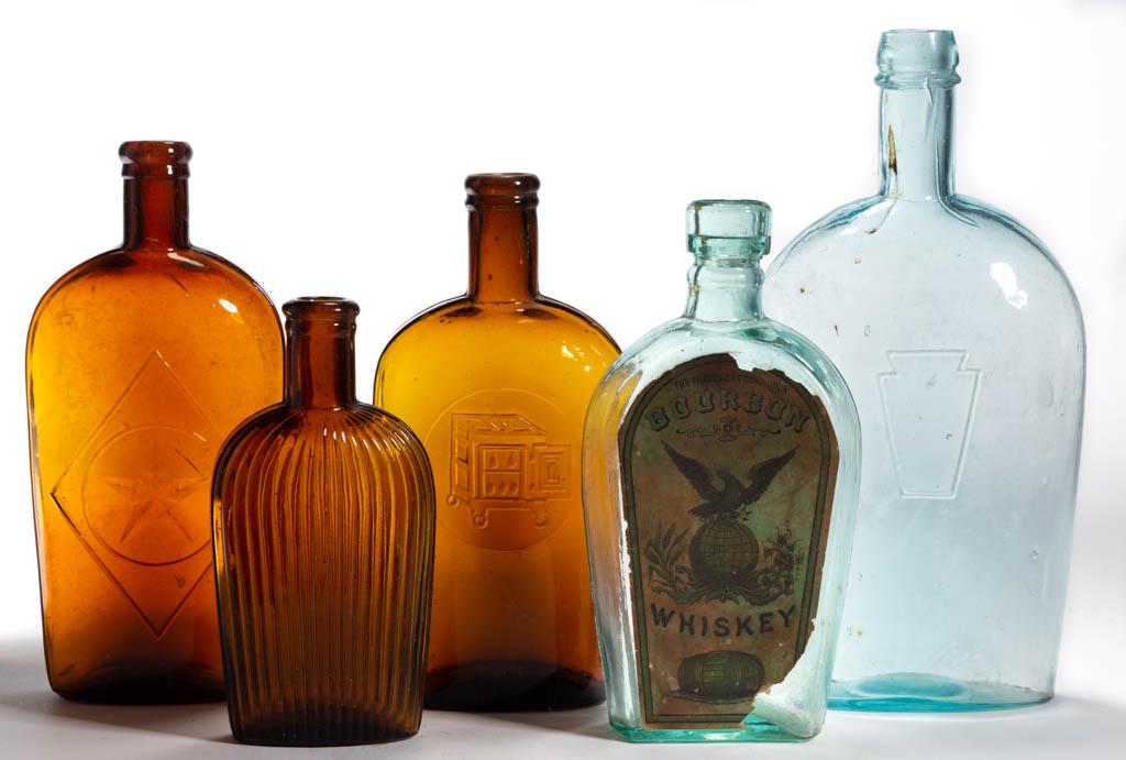 ASSORTED WHISKEY FLASKS, LOT OF FIVE: ASSORTED WHISKEY FLASKS, LOT OF FIVE, amber, aquamarine, and light green, comprising a quart with keystone, a pint with Traveller's Companion Bourbon Whiskey label, and three strap-side examples, feat
