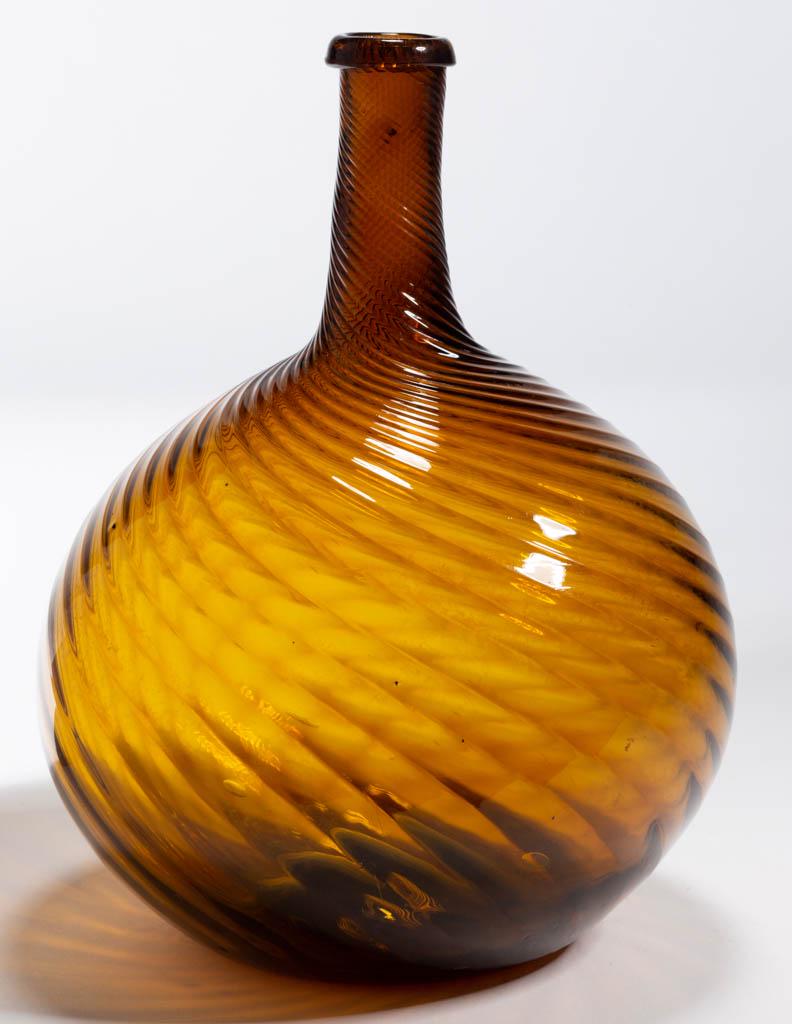 PATTERN-MOLDED GLOBULAR-FORM BOTTLE: PATTERN-MOLDED GLOBULAR-FORM BOTTLE, bright topaz/yellow amber, 24 ribs swirled tightly to the left, medium neck tapering slightly to a delicate turned-over mouth, rough pontil mark. Midwestern, possi