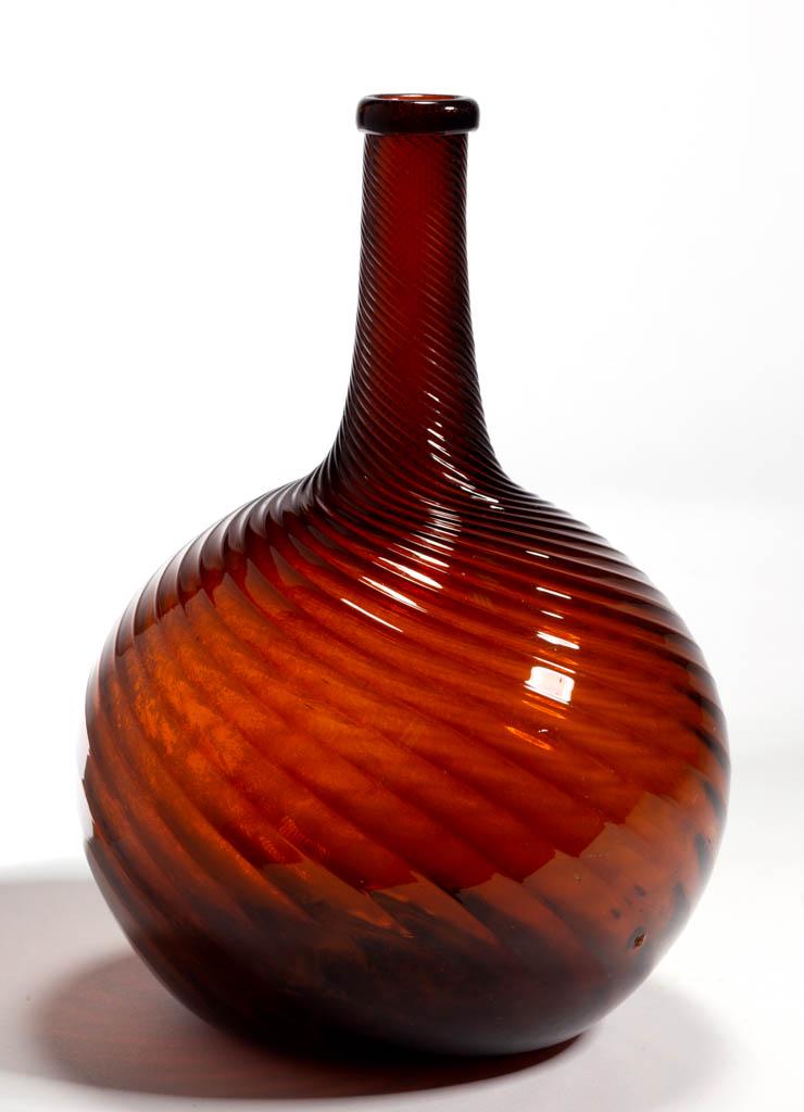 PATTERN-MOLDED GLOBULAR-FORM BOTTLE: PATTERN-MOLDED GLOBULAR-FORM BOTTLE, red amber, 24 ribs swirled tightly to the left, medium neck tapering slightly to a delicate turned-over mouth, rough pontil mark. Midwestern, possibly White Glass 