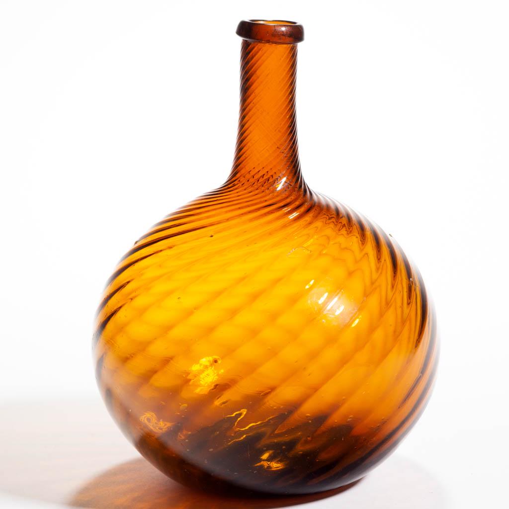 PATTERN-MOLDED GLOBULAR-FORM BOTTLE: PATTERN-MOLDED GLOBULAR-FORM BOTTLE, golden amber, 24 ribs swirled to the right, medium neck tapering slightly to a delicate turned-over mouth, rough pontil mark. Midwestern, possibly White Glass Work