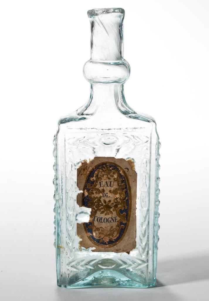 BLOWN-MOLDED FIGURED COMMERCIAL COLOGNE BOTTLE: BLOWN-MOLDED FIGURED COMMERCIAL COLOGNE BOTTLE, aquamarine, rectangular form with vertical plume on three sides, bulbed neck and plain, tooled mouth, rough pontil mark. Retains original "EAU / DE / CO
