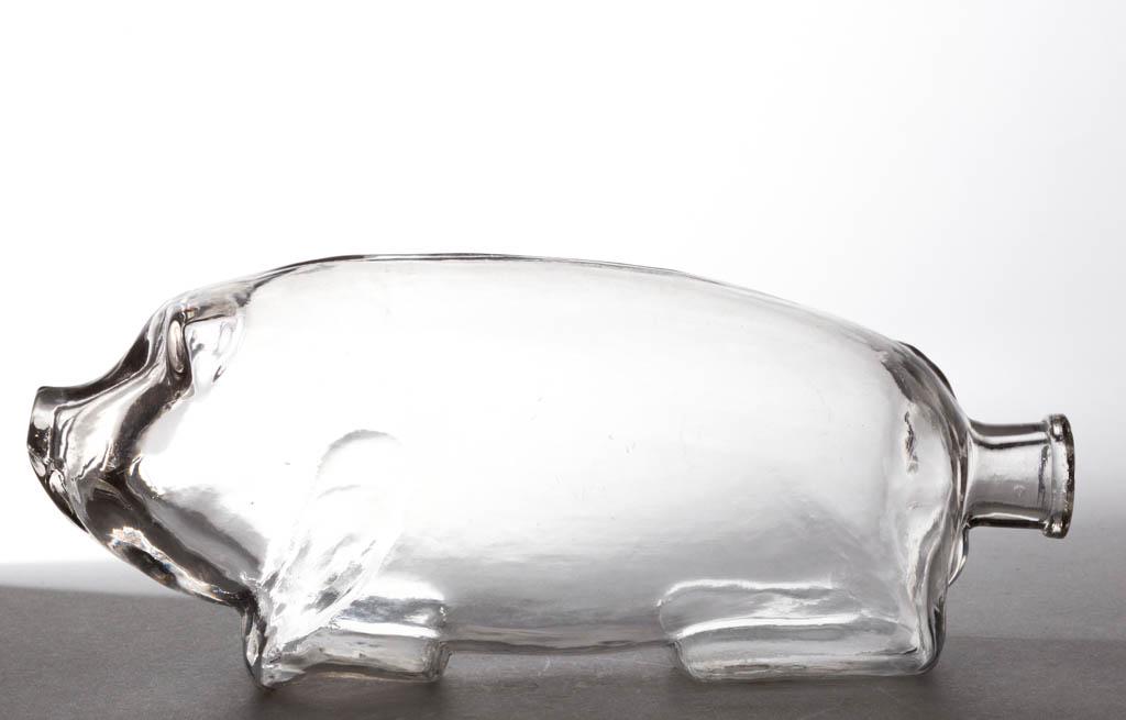 PIG FIGURAL BOTTLE: PIG FIGURAL BOTTLE, colorless, unembossed variation of Suffolk Bitters, squared mouth. Circa 1890. 3 1/2" H, 9 3/4" L.Undamaged.Literature: Parallels Ring/Ham - Bitters Bottles, p. 523, fig. S-217.Pro