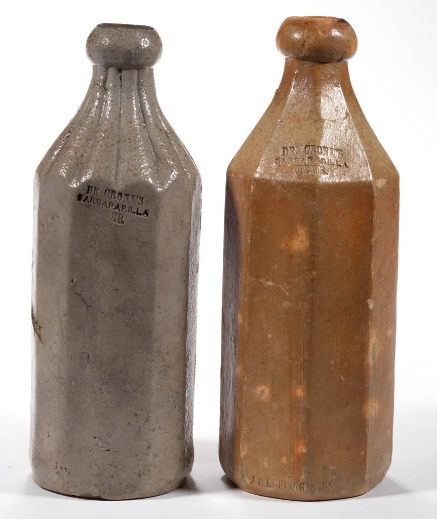 CRONK'S STONEWARE SARSAPARILLA BEER BOTTLES, LOT OF TWO: CRONK'S STONEWARE SARSAPARILLA BEER BOTTLES, LOT OF TWO, salt-glazed, each stamped "DR. CRONK'S / SARSAPARILLA / BEER" at shoulder, comprising a grey 12-sided example with lobed shoulder, and a tan ex