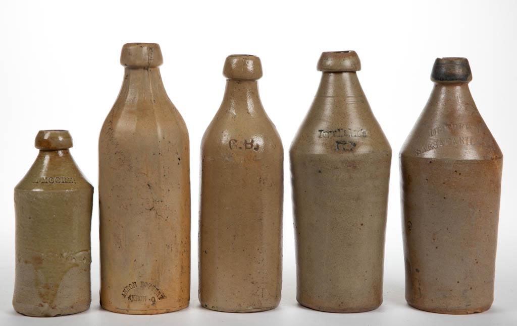 ASSORTED STONEWARE SARSAPARILLA / BEER BOTTLES, LOT OF: ASSORTED STONEWARE SARSAPARILLA / BEER BOTTLES, LOT OF FIVE, salt-glazed, stamped for De Freest, M. Moore, G.B. Akron Pottery Co., and illegible. Second half 19th century. 7 1/4" to 10 3/4" H. De Free
