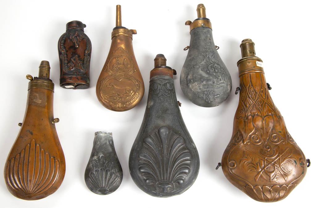 ASSORTED TIN AND BRASS POWDER FLASKS, LOT OF SEVEN: ASSORTED TIN AND BRASS POWDER FLASKS, LOT OF SEVEN, including one with double-sided embossed decoration of bleeding hearts, stamped "Wm. B. SHERTZER, COLUMBIA, PA.", and "G. & J. W. Hawksley / Sheffie