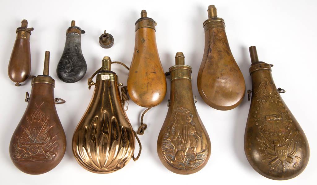 ASSORTED TIN AND BRASS POWDER FLASKS, LOT OF EIGHT: ASSORTED TIN AND BRASS POWDER FLASKS, LOT OF EIGHT, including a Model 1855 "Peace and Friendship" example, and one with embossed decoration of crossing American Flags with a cannon. 19th century. Frie