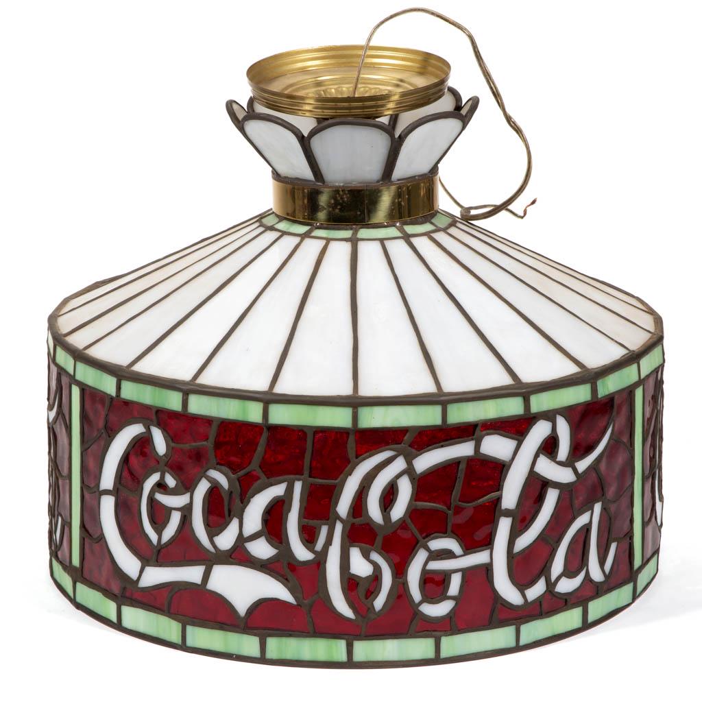 COCA-COLA ADVERTISING LEADED- AND STAINED-GLASS HANGING: COCA-COLA ADVERTISING LEADED- AND STAINED-GLASS HANGING LAMP, metal collar marked "PROPERTY OF THE / COCA-COLA COMPANY / TO BE RETURNED ON DEMAND". Second half 20th century. 13" HOA, 16 1/4" D. Excell