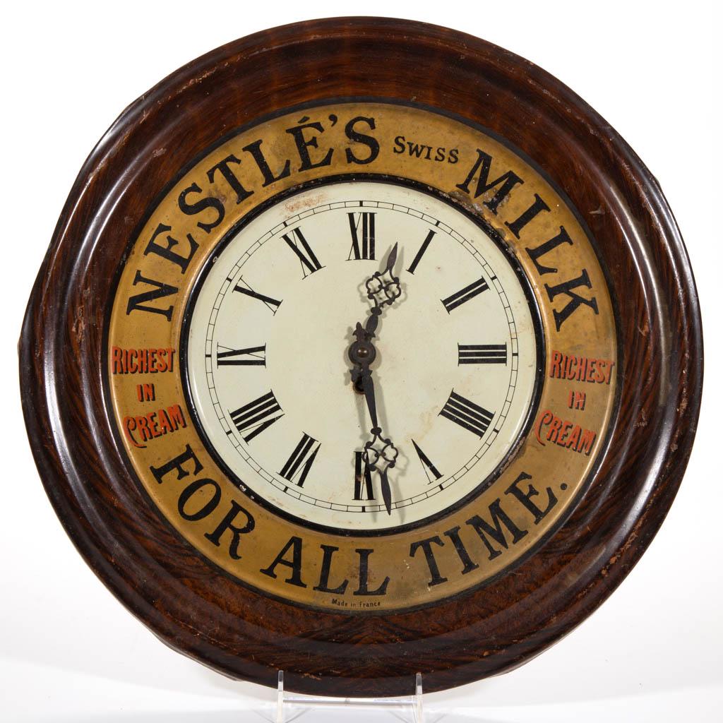 NESTLE'S SWISS MILK ADVERTISING WALL CLOCK: NESTLE'S SWISS MILK ADVERTISING WALL CLOCK, lithograph on tin, marked "Made in France", pendulum present. First quarter 20th century. 19" D. Good overall condition with scattered minor paint loss, mod