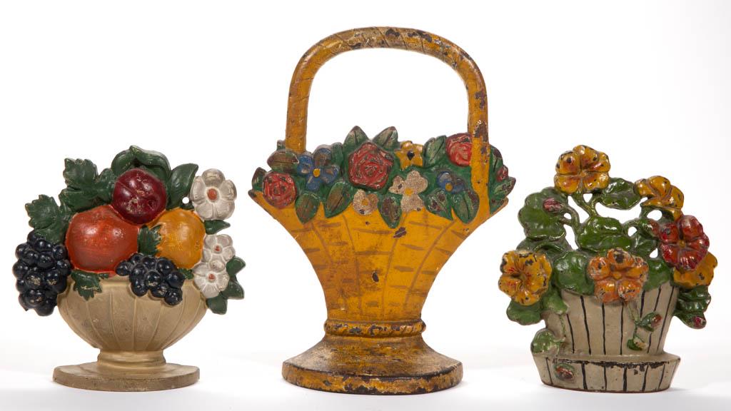 HUBLEY CAST-IRON FIGURAL FLOWER BASKET DOORSTOPS, LOT: HUBLEY CAST-IRON FIGURAL FLOWER BASKET DOORSTOPS, LOT OF TWO, each retaining likely original painted surface. Together with a cast-iron fruit bowl doorstop, retaining likely original paint. Three piec