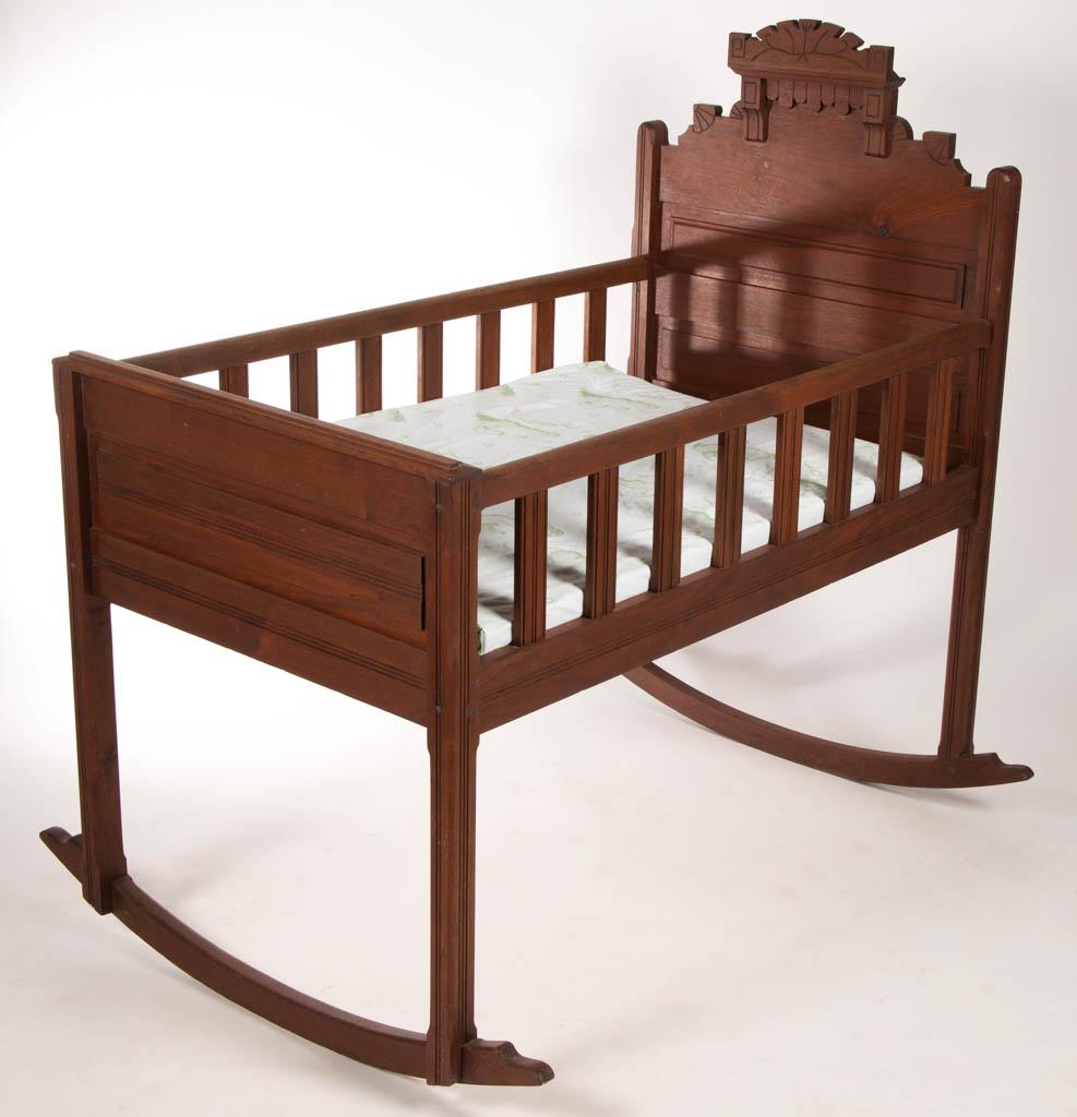 SHENANDOAH VALLEY OF VIRGINIA VICTORIAN WALNUT YOUTH: SHENANDOAH VALLEY OF VIRGINIA VICTORIAN WALNUT YOUTH CRADLE, with shaped headboard. Retains an old surface with warm color. Fourth quarter 19th century. 47 3/4" HOA, 27 1/4" WOA, 47" LOA. Very good ov