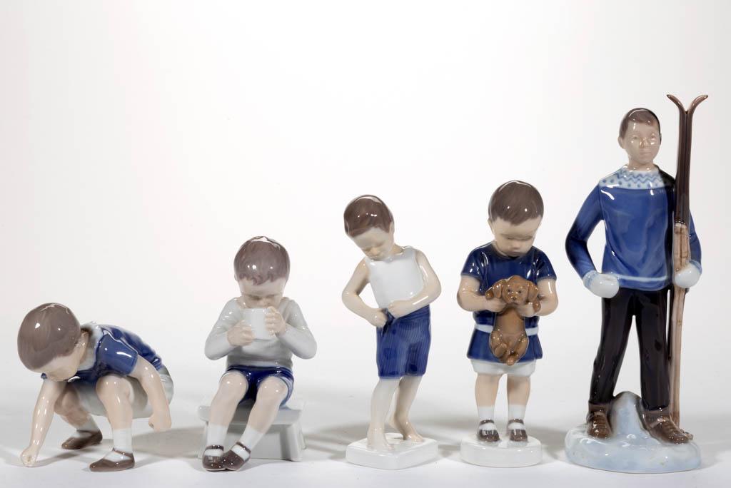 DANISH BING & GRONDAHL HAND-PAINTED PORCELAIN FIGURES,: DANISH BING & GRONDAHL HAND-PAINTED PORCELAIN FIGURES, LOT OF FIVE, comprising boys in various poses including one holding a puppy (#1747), one fastening his shorts (#1759), one holding a pair of skis