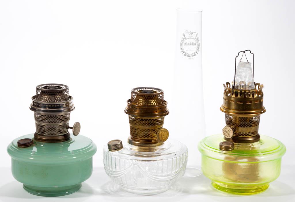 ALADDIN GLASS KEROSENE LAMP FONTS, LOT OF THREE: ALADDIN GLASS KEROSENE LAMP FONTS, LOT OF THREE, comprising a colorless C-164, a Jade Moonstone, and a Vaseline (reacts under black light) example with a signed Lox-on chimney. The Mantle Lamp Company