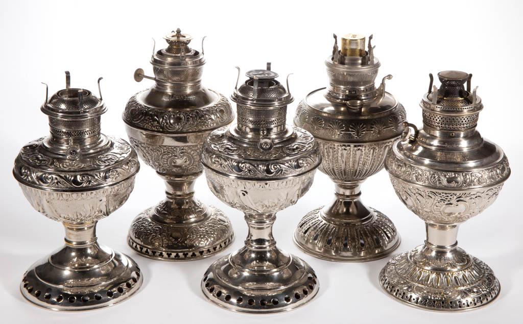 ASSORTED EMBOSSED NICKEL KEROSENE STAND LAMPS, LOT OF: ASSORTED EMBOSSED NICKEL KEROSENE STAND LAMPS, LOT OF FIVE, including a "NEW JUNO", a pair of Bristol examples, and a "MILLER'S VESTAL". Each being fitted with a period burner, four having a correct f