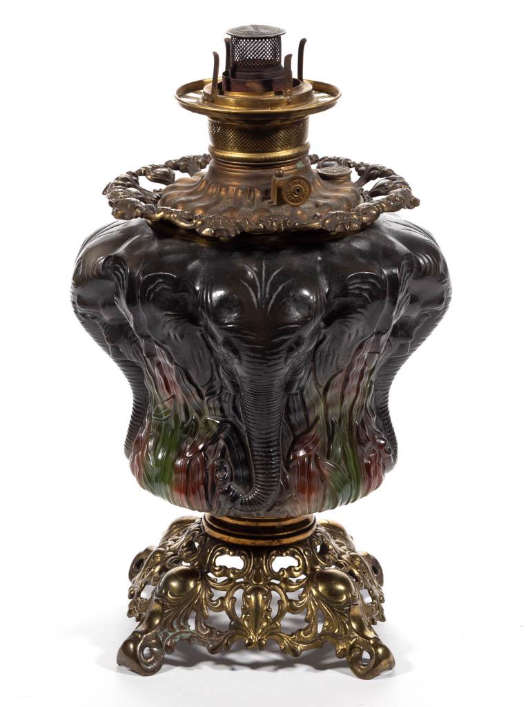 CONSOLIDATED ELEPHANT KEROSENE GONE WITH THE WIND /: CONSOLIDATED ELEPHANT KEROSENE GONE WITH THE WIND / PARLOR LAMP BASE, opaque white with a polychrome ground and grey elephant heads, brass connector and brass openwork scrolling and medallion foot, ca
