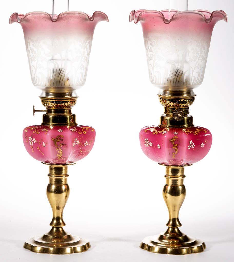 VICTORIAN DECORATED PAIR OF KEROSENE PEG LAMPS,: VICTORIAN DECORATED PAIR OF KEROSENE PEG LAMPS,, cased dark to light rose with stylized enamel and gilt decoration, hexagonal-form fonts with concave sides, period No. 2 collars, brass candlesticks wi