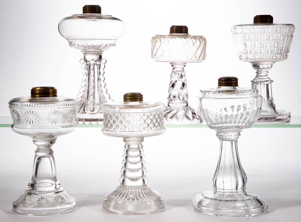 ASSORTED GLASS KEROSENE STAND LAMPS, LOT OF SIX: ASSORTED GLASS KEROSENE STAND LAMPS, LOT OF SIX, colorless, including a Picture Window, a Cross Lens, and a Sharon Panel Base with Rib Font. Various makers. Late 19th/first quarter 20th century. 7" to