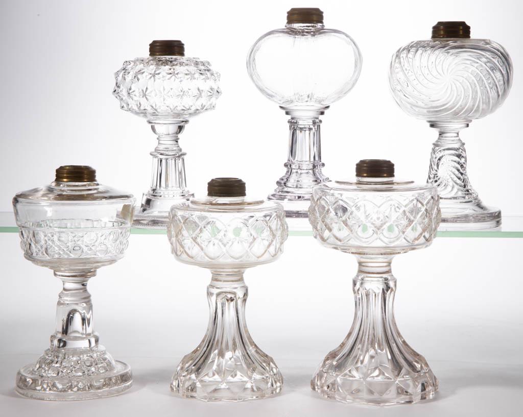 ASSORTED GLASS KEROSENE STAND LAMPS, LOT OF SIX: ASSORTED GLASS KEROSENE STAND LAMPS, LOT OF SIX, colorless, including two Ava, a Tudor, and a Whirlpool. Various makers. Late 19th/first quarter 20th century. 7" to 8 1/4" H. Overall Star having a sin