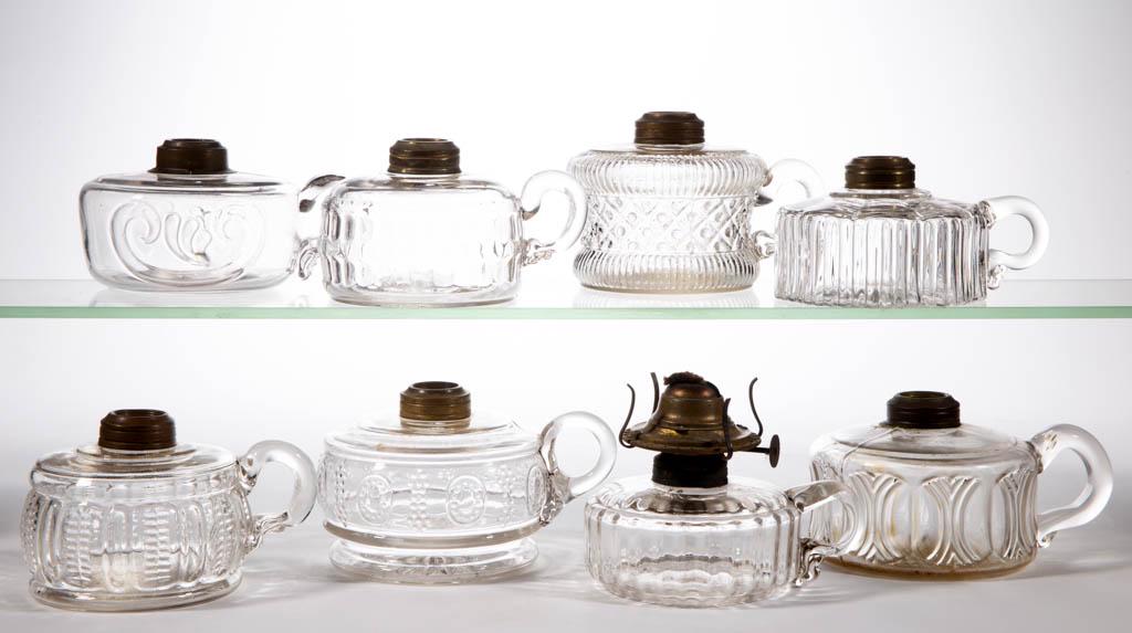 ASSORTED GLASS KEROSENE FINGER LAMPS, LOT OF EIGHT: ASSORTED GLASS KEROSENE FINGER LAMPS, LOT OF EIGHT, colorless, including a Curved Rib Panel, a Riven Band, a Zipper and Rib, and a Beaded Diamond and Rib Band. Various makers. Fourth quarter 19th/firs
