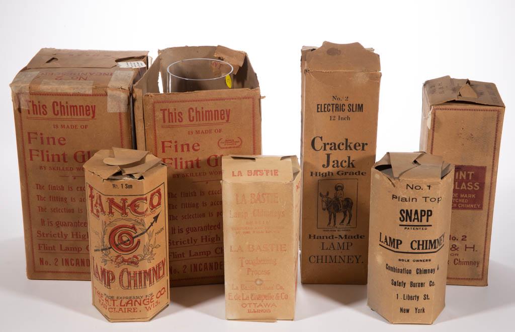 ASSORTED FLINT GLASS SLIP CHIMNEYS, LOT OF SEVEN: ASSORTED FLINT GLASS SLIP CHIMNEYS, LOT OF SEVEN, including a "NO. 2/B&H", a "NO. 89 B&H/MAMMOTH AND INCANDESCENT", a "Fisher, Bruce & Company" No. 2, and a "LA BASTIE", each in the original box. Vari