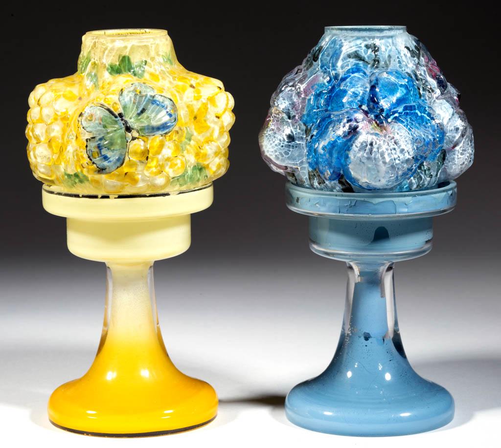 PAIRPOINT PUFFY FLORAL SHADE PEDESTAL CANDLE / FAIRY: PAIRPOINT PUFFY FLORAL SHADE PEDESTAL CANDLE / FAIRY LAMPS, LOT OF TWO, colorless with polychrome reverse painting, comprising a shade with lilacs and butterflies, and a shade with four pansies and le