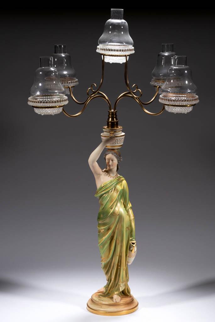 ROYAL WORCESTER CERAMIC FIGURAL STANDARD FOUR-ARM FAIRY: ROYAL WORCESTER CERAMIC FIGURAL STANDARD FOUR-ARM FAIRY LAMP, gilt decoration, "Grecian Water Carrier" female figure holding an urn to her side and balancing an urn on her head, topped with a brass sc