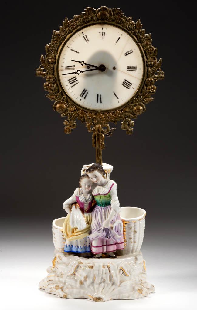 GERMAN PORCELAIN FIGURAL SMOKING STAND FAIRY LAMP CLOCK: GERMAN PORCELAIN FIGURAL SMOKING STAND FAIRY LAMP CLOCK, cast-brass frame with brushed finish, rear adjustable arm with candle holder and candle, key-wind movement with key, translucent glass dial wit