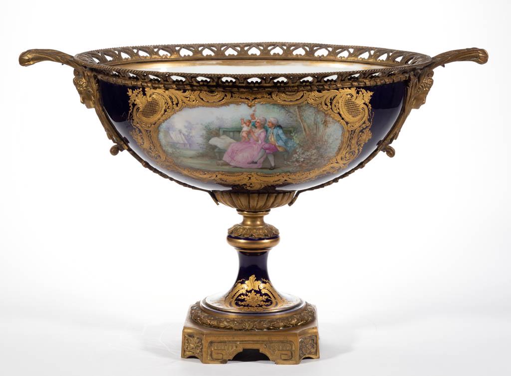 FRENCH SEVRES-STYLE PORCELAIN ORMOLU-MOUNTED BOLTED: FRENCH SEVRES-STYLE PORCELAIN ORMOLU-MOUNTED BOLTED CENTERPIECE, having oval form with elaborate gilt decoration on cobalt ground, and open flaring handles featuring a molded woman's face, having poly