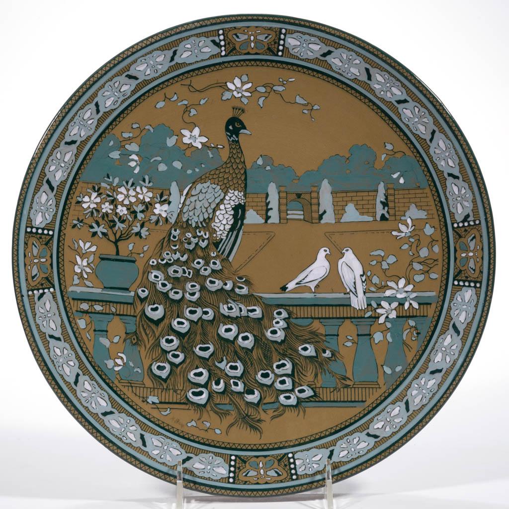 AMERICAN BUFFALO POTTERY DELDARE CERAMIC PLAQUE: AMERICAN BUFFALO POTTERY DELDARE CERAMIC PLAQUE, featuring lovely garden setting showing a peacock and two doves, having butterfly border design with two drilled holes to foot ring for hanging. Signed