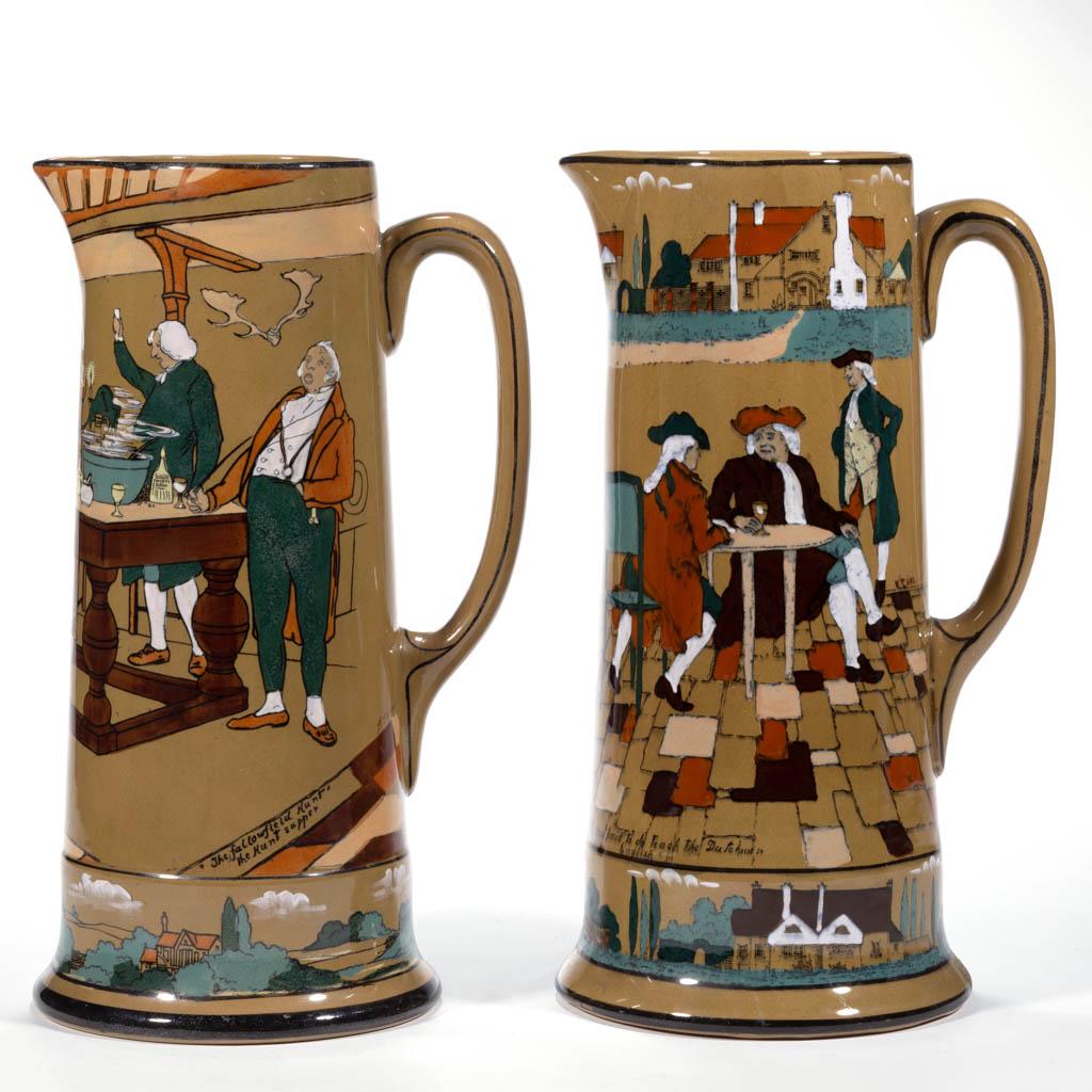 AMERICAN BUFFALO POTTERY DELDARE CERAMIC TANKARD: AMERICAN BUFFALO POTTERY DELDARE CERAMIC TANKARD PITCHERS, LOT OF TWO, comprising one example featuring "Ye Olden Days" tavern scene entitled "The Great Controversy" and "All you have to do to teach t