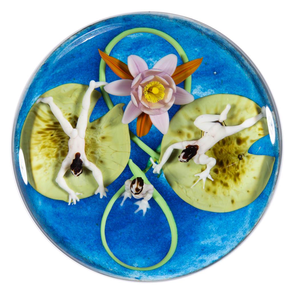 JIM D'ONOFRIO SPRITES AND LILY PADS LAMPWORK STUDIO ART: JIM D'ONOFRIO SPRITES AND LILY PADS LAMPWORK STUDIO ART GLASS PAPERWEIGHT, colorless, two green lily pads with a bloomed pink flower with yellow stamen, each lily pad with a laying human figure/sprite