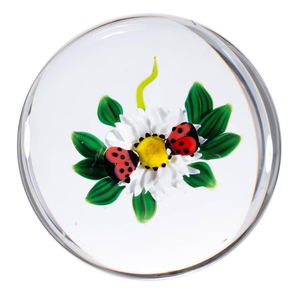 KEN ROSENFELD LADYBUGS AND FLOWER LAMPWORK STUDIO ART: KEN ROSENFELD LADYBUGS AND FLOWER LAMPWORK STUDIO ART GLASS PAPERWEIGHT, colorless, two small ladybugs standing on a bloomed flower with white petals and a yellow stamen, green leaves to the sides and