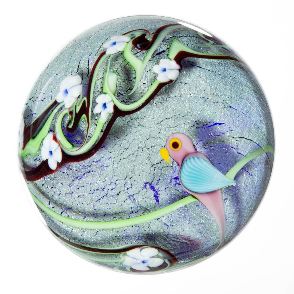 ORIENT AND FLUME PARROT LAMPWORK STUDIO ART GLASS: ORIENT AND FLUME PARROT LAMPWORK STUDIO ART GLASS PAPERWEIGHT, colorless with a craquelled blue iridescent ground, depicting a blue and lavender perched parrot, twisting green and maroon vines with 11