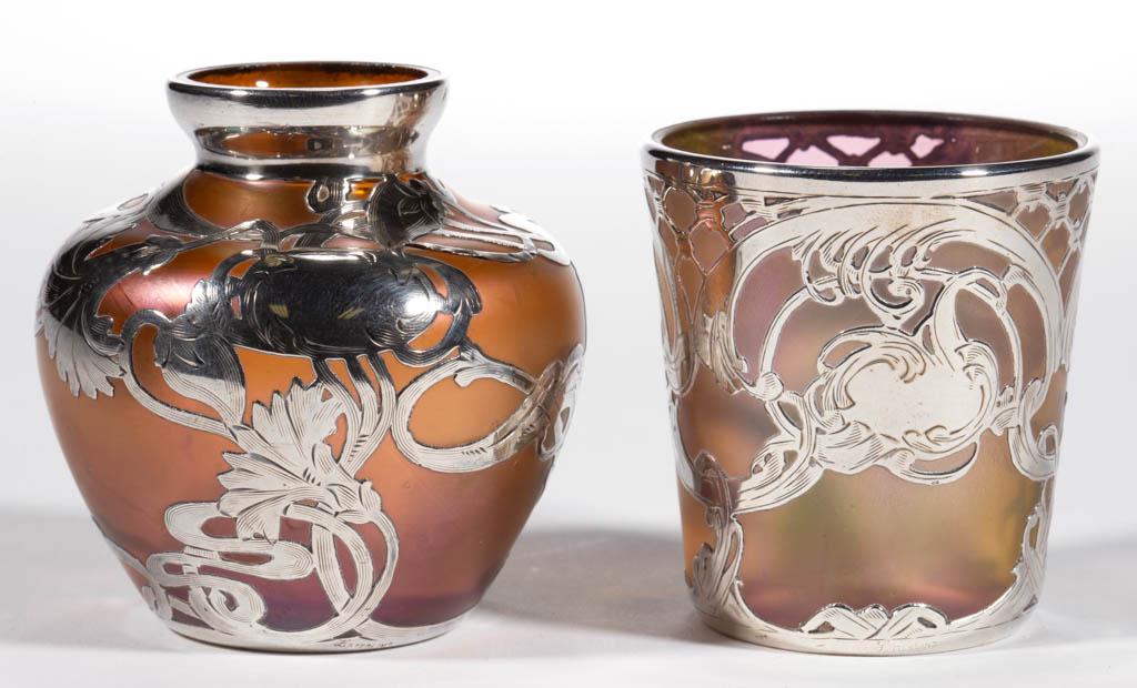 LOETZ ATTRIBUTED RAINBOW IRIDESCENT ART GLASS -: LOETZ ATTRIBUTED RAINBOW IRIDESCENT ART GLASS - SILVER-OVERLAY CABINET ARTICLES, LOT OF TWO, comprising a diminutive urn form and a tumbler form, vase having floral overlay decoration, tumbler having 