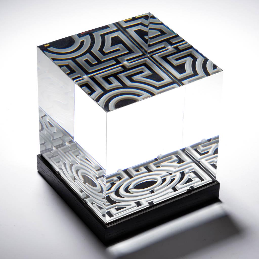 STEUBEN CRYSTAL THE CHALLENGE / LABYRINTH CUBE ART: STEUBEN CRYSTAL THE CHALLENGE / LABYRINTH CUBE ART GLASS SCULPTURE, colorless, black base, engraved labyrinth to the base, sitting on a black wooden base with cloth overlay, signed "Steuben" to one ba