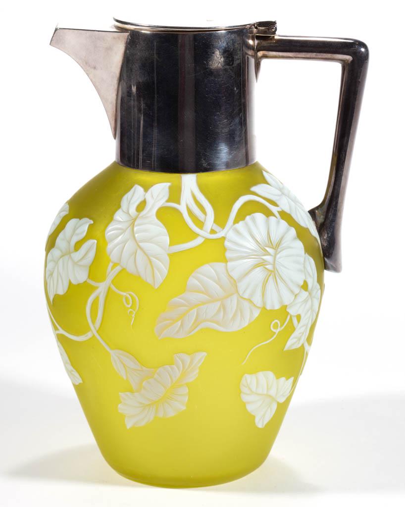 THOMAS WEBB CAMEO ART GLASS SYRUP PITCHER: THOMAS WEBB CAMEO ART GLASS SYRUP PITCHER, white to citron, ovoid form with foliate vines with blooming trumpet flowers, fitted with a silver-plate lid and handle with a trademark stamped to the inter