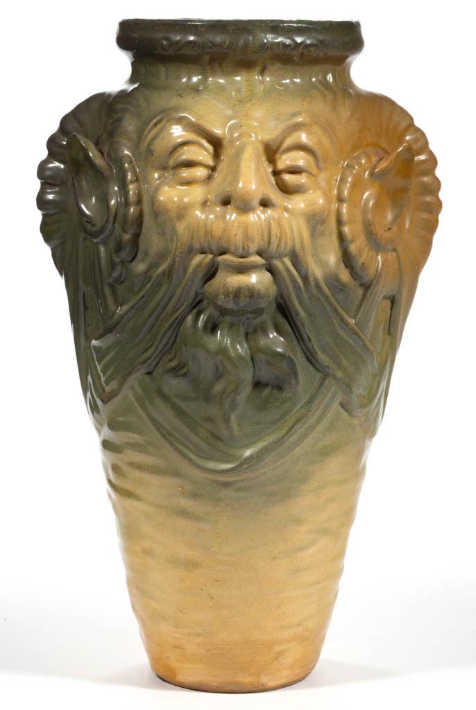 AMERICAN GROTESQUE ART POTTERY VASE: AMERICAN GROTESQUE ART POTTERY VASE, featuring a molded bearded face to each side, having protruding ears encircled by horns, with yellow and green glaze. Unmarked. Late 19th/first half 20th century.