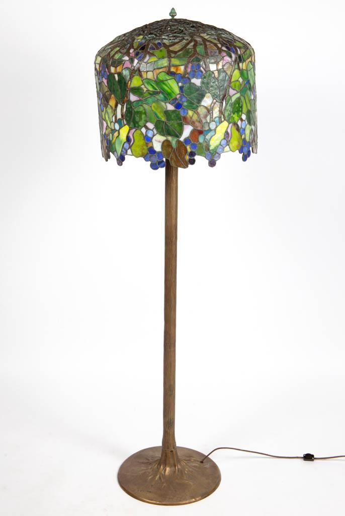 TIFFANY STUDIOS REPRODUCTION GRAPE LEADED-GLASS: TIFFANY STUDIOS REPRODUCTION GRAPE LEADED-GLASS ELECTRIC FLOOR LAMP, polychrome overhanging shade, large trunk-form metal base, three-socket cluster with modern sockets, unsigned. Maker unverified. 20