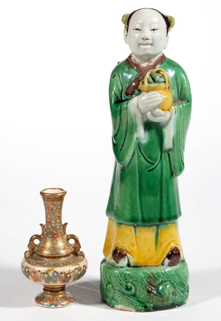 CHINESE LAN CAIHE PORCELAIN FIGURE: CHINESE LAN CAIHE PORCELAIN FIGURE, standing on a molded circular base, having bold green, yellow, and brown decoration, cradling a basket of fruit/flowers with hair in two buns. Open bottomed. Togeth
