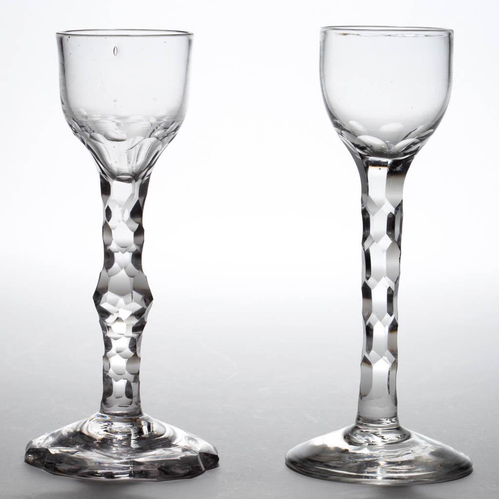 ENGLISH FREE-BLOWN FACET-STEM WINE GLASSES, LOT OF TWO: ENGLISH FREE-BLOWN FACET-STEM WINE GLASSES, LOT OF TWO, colorless lead glass, each with ogee bowl, one with scale-cut base, each raised on a hexagonal-faceted stem, one with central knop and scalloped