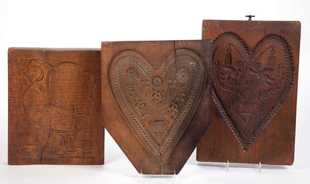 SPRINGERLE CARVED TREEN / WOOD CAKE / PASTRY BOARDS,: SPRINGERLE CARVED TREEN / WOOD CAKE / PASTRY BOARDS, LOT OF THREE, comprising a double-sided example with different heart design on each side, and two single-sided examples with one having a potted fl