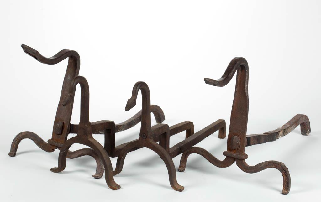 AMERICAN SNAKE-FORM WROUGHT-IRON ANDIRONS, TWO PAIRS: AMERICAN SNAKE-FORM WROUGHT-IRON ANDIRONS, TWO PAIRS, each with arched neck terminating in a snake head, and raised on arched feet, larger pair with inlaid brass eyes, smaller pair with punched eyes a