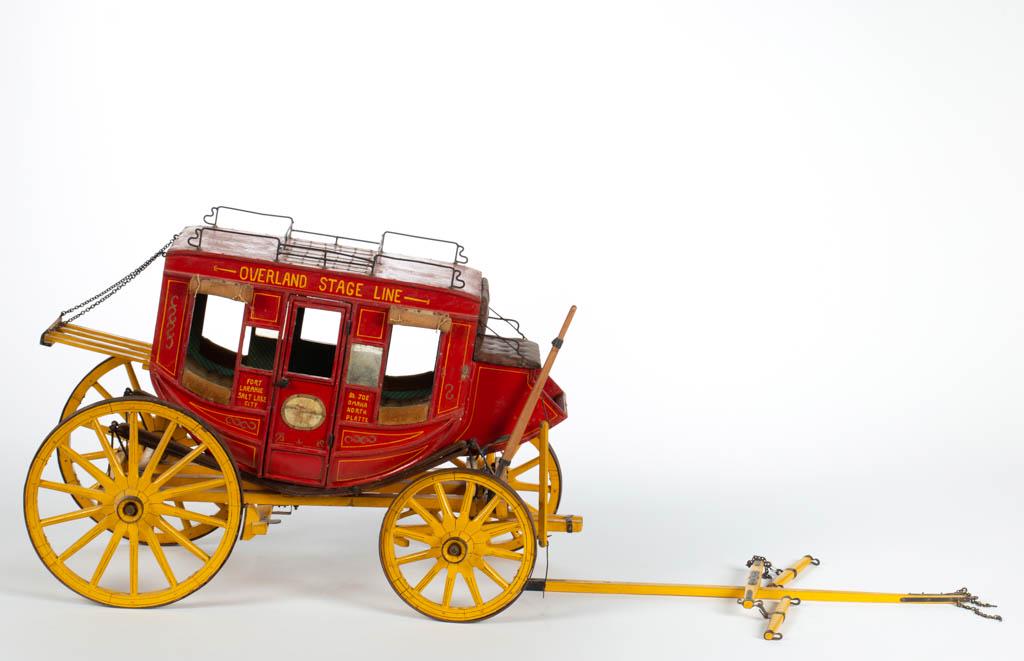 AMERICAN CARVED AND PAINTED WOOD STAGE COACH MODEL: AMERICAN CARVED AND PAINTED WOOD STAGE COACH MODEL, a finely detailed copy of an "Overland Stage Line" coach with upholstered and papered interior, tufted-leather driver's seat, canvas roll-down windo