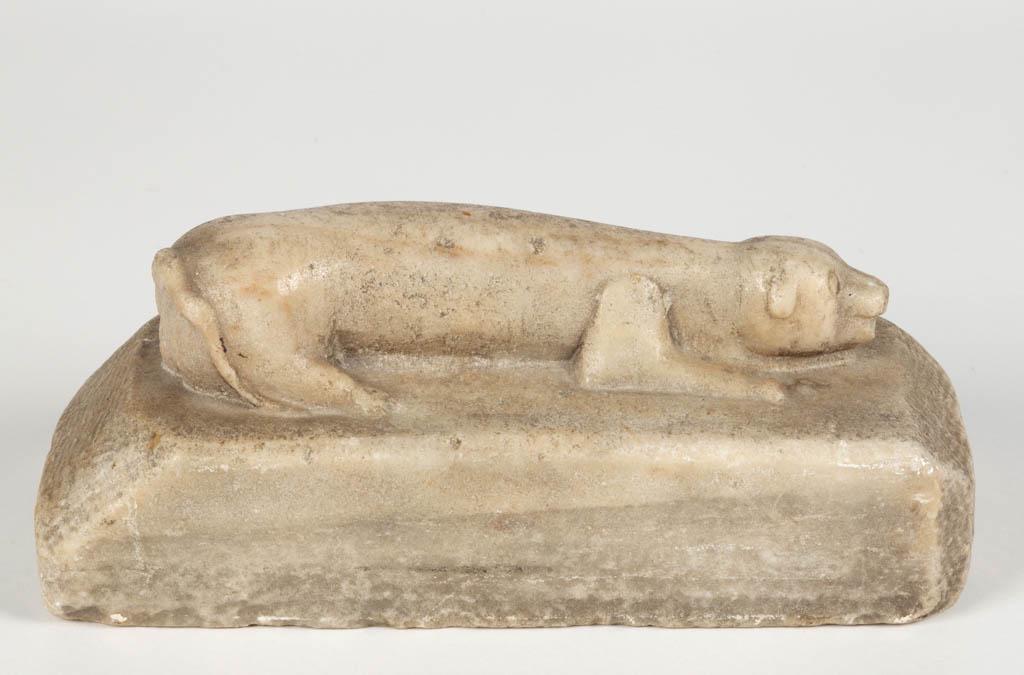 AMERICAN FOLK ART CARVED MARBLE GRAVE MARKER / DOOR: AMERICAN FOLK ART CARVED MARBLE GRAVE MARKER / DOOR STOP, reclining dog-like figure on a rectangular base. Possibly Ohio. Second half 19th century. 4 3/8" HOA, 10 3/4" x 4 3/4" base. Good overall cond