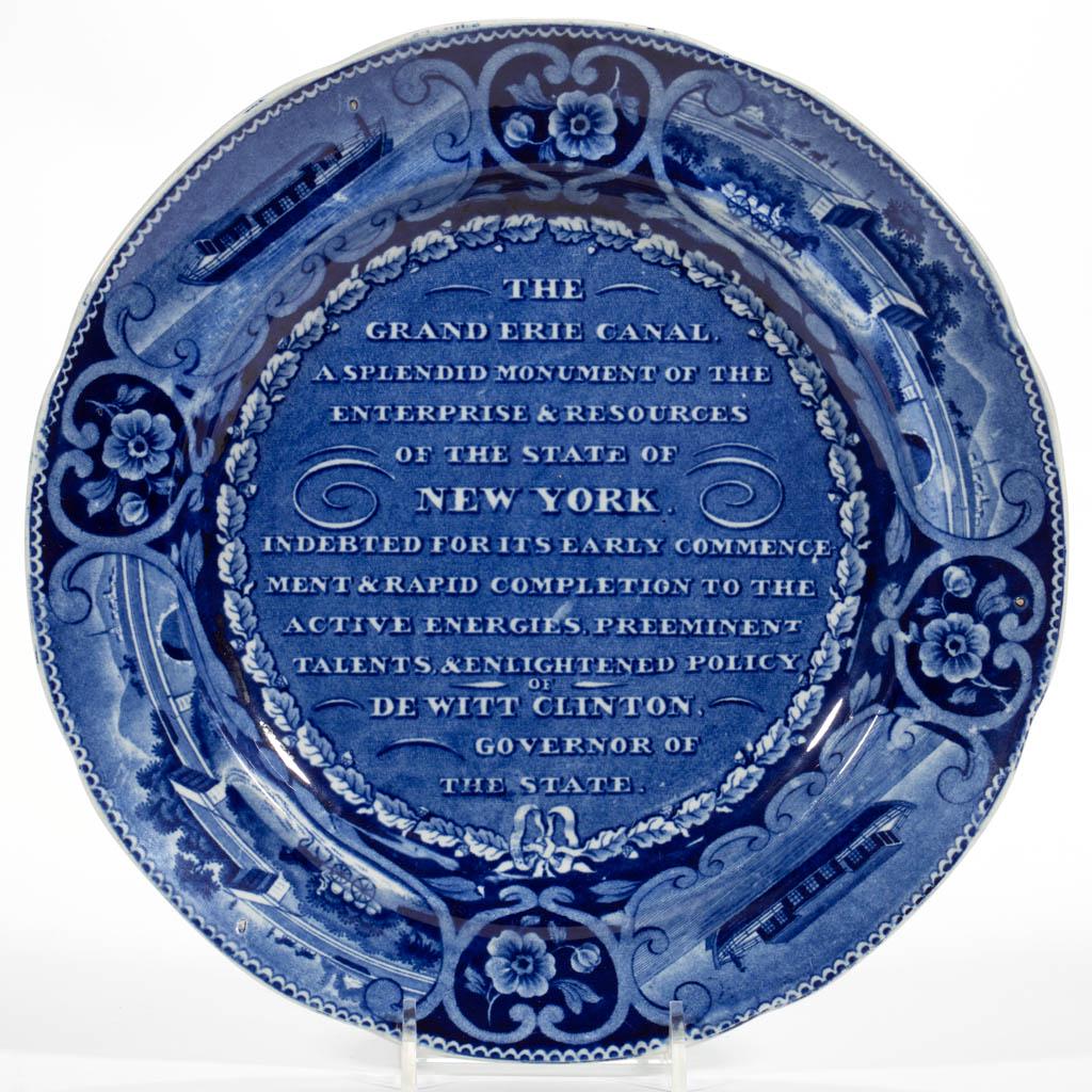 ENGLISH STAFFORDSHIRE PEARLWARE TRANSFER-PRINTED: ENGLISH STAFFORDSHIRE PEARLWARE TRANSFER-PRINTED AMERICAN HISTORICAL CERAMIC PLATE, having dark blue transfer design featuring the Erie Canal inscription, with "DE WITT CLINTON / GOVERNOR OF / THE STA