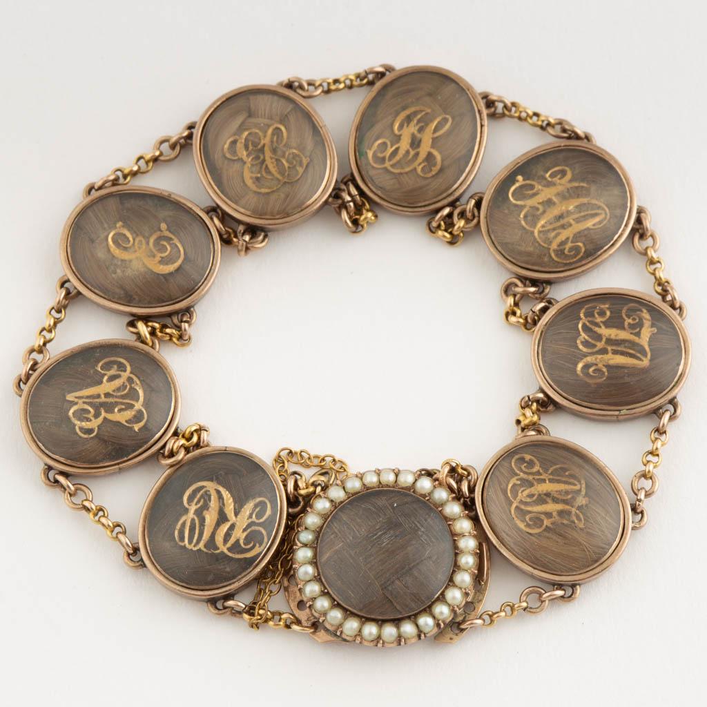 VICTORIAN HAIR-WORK MOURNING / FRIENDSHIP BRACELET: VICTORIAN HAIR-WORK MOURNING / FRIENDSHIP BRACELET, eight oval links housing encased hair with applied gold-toned initials, connected by double chains, having a tab-insert round box clasp with safety 