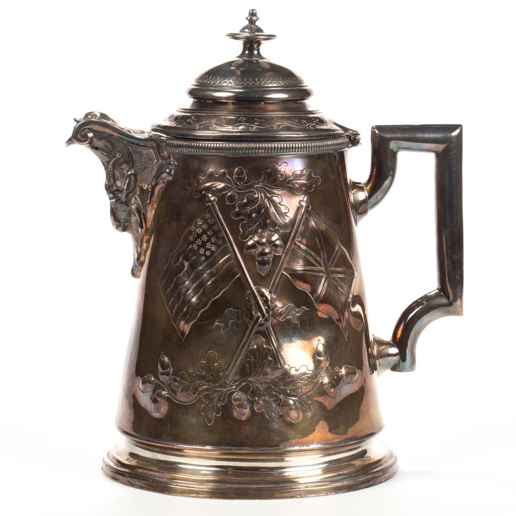 VICTORIAN SILVER-PLATED ICE WATER PITCHER: VICTORIAN SILVER-PLATED ICE WATER PITCHER, cylindrical well featuring slight repousse and engraved designs featuring crossed 21-star American flag and British Union Jack flag looped together by a wrea