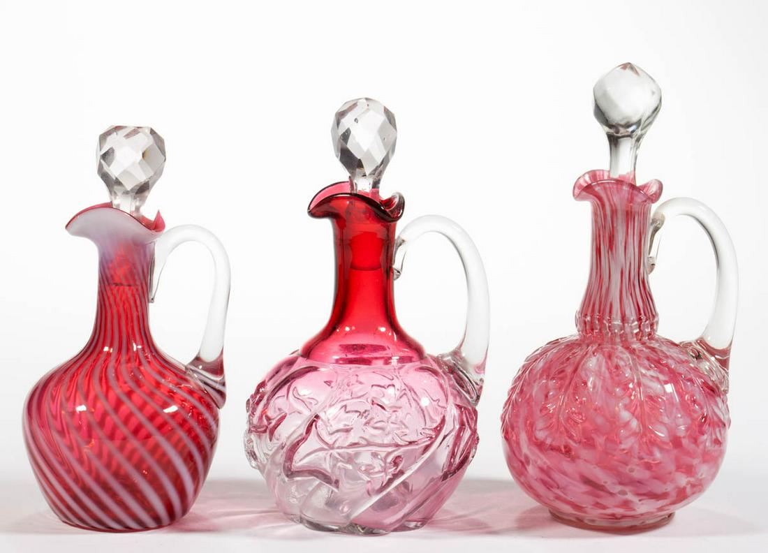 ASSORTED VICTORIAN GLASS CRUETS, LOT OF THREE: ASSORTED VICTORIAN GLASS CRUETS, LOT OF THREE, comprising a rubina Royal Ivy, a cranberry with opal spatter Leaf Umbrella, and a cranberry opalescent Swirl, each having a cut or pressed-faceted stoppe
