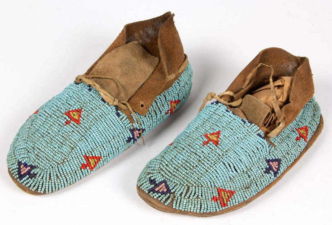 PAIR OF NATIVE AMERICAN / PLAINS INDIAN BEADED CHILD'S: PAIR OF NATIVE AMERICAN / PLAINS INDIAN BEADED CHILD'S MOCCASINS, sinew sewn, decorated with beadwork in blue, red, greasy yellow, and pink geometric designs on a turquoise ground. Fourth quarter 19th